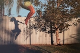 Coloured photo of child's shadow on a swing in a backyard.