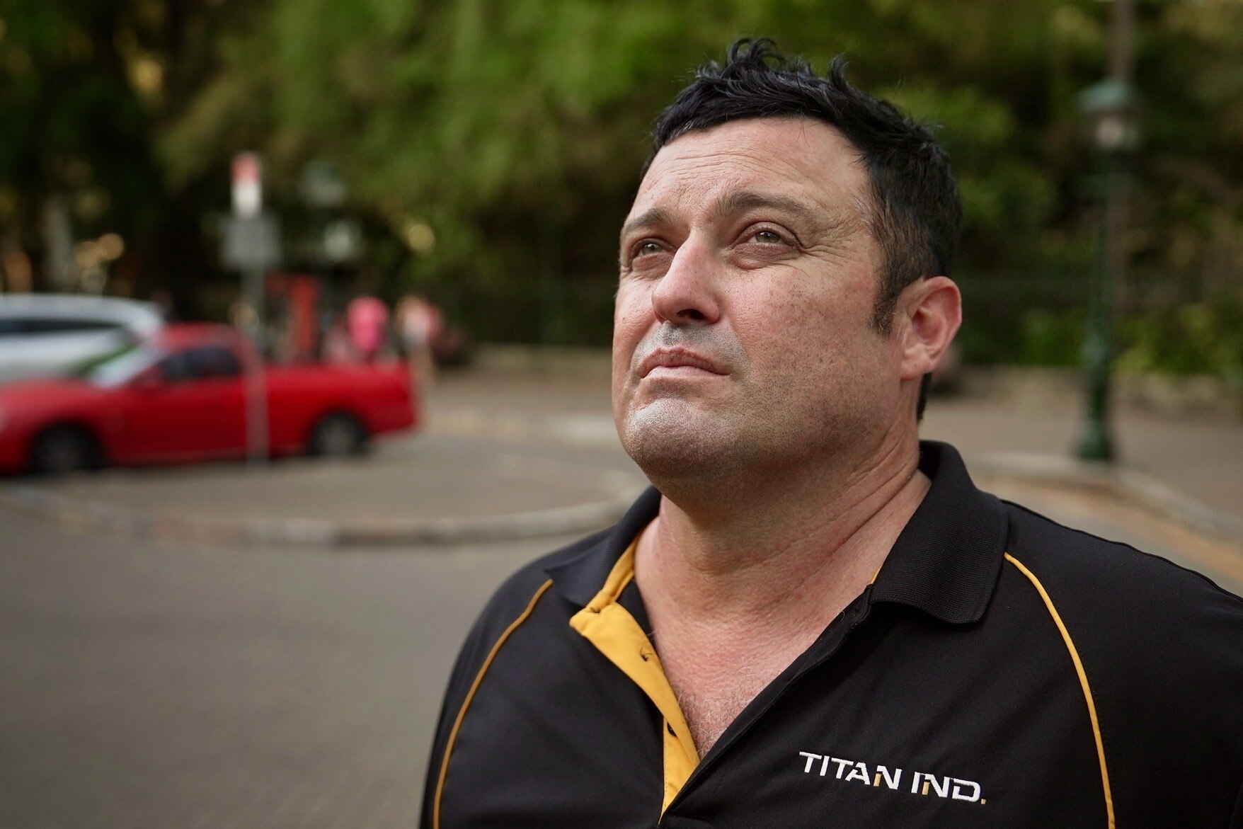A man in a tradesman's shirt, looking upwards.