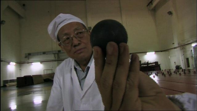 A man in white protective clothing holds a black disk