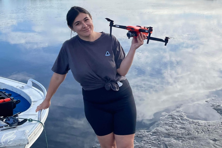 woman holding drone infront of water