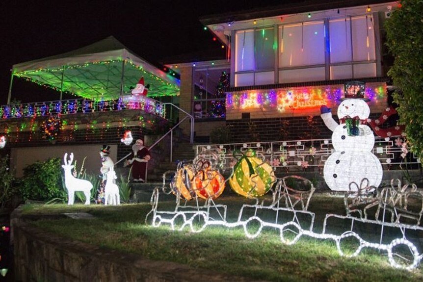 A home pictured at night with coloured lights in the windows and a lit up snowman, reindeer and baubles on the lawn.
