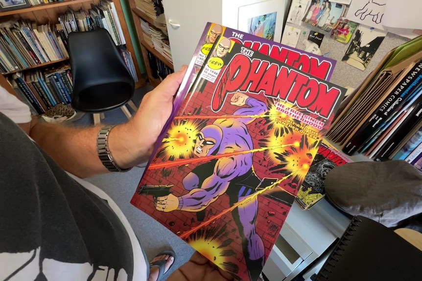 A man using pencil to draw The Phantom comic book panels