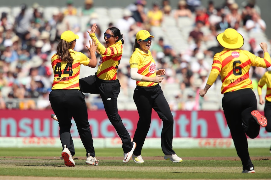 La jugadora de cricket australiana Alana King salta en el aire para chocar los cinco con una compañera de equipo mientras celebra su hat-trick.