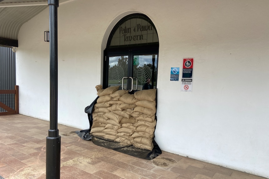 A pub door with sandbags stacked in front of it.