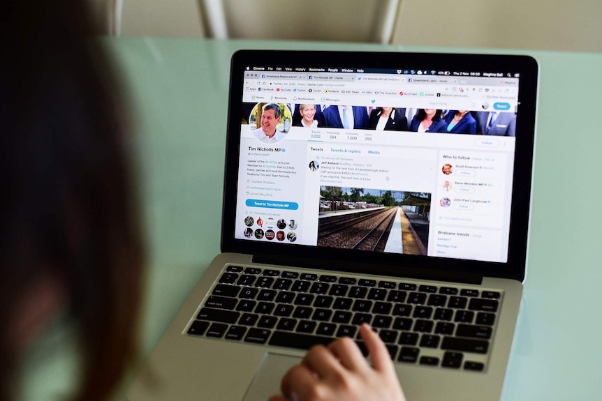 Photo of open laptop with a person's hand in view looking at the Facebook page of Queensland MP Tim Nicholls.