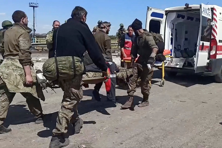 Żołnierze ukraińscy niosą rannego towarzysza po opuszczeniu oblężonej huty w Azowstalu.