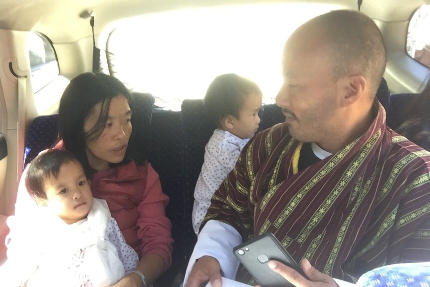 Parents and twins sitting in backseat of car.