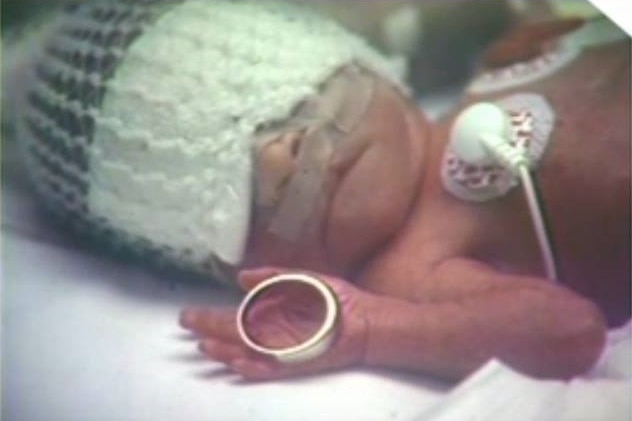 Rachelle Mainse as a newborn in 1988 holding her father's wedding ring in palm of her hand