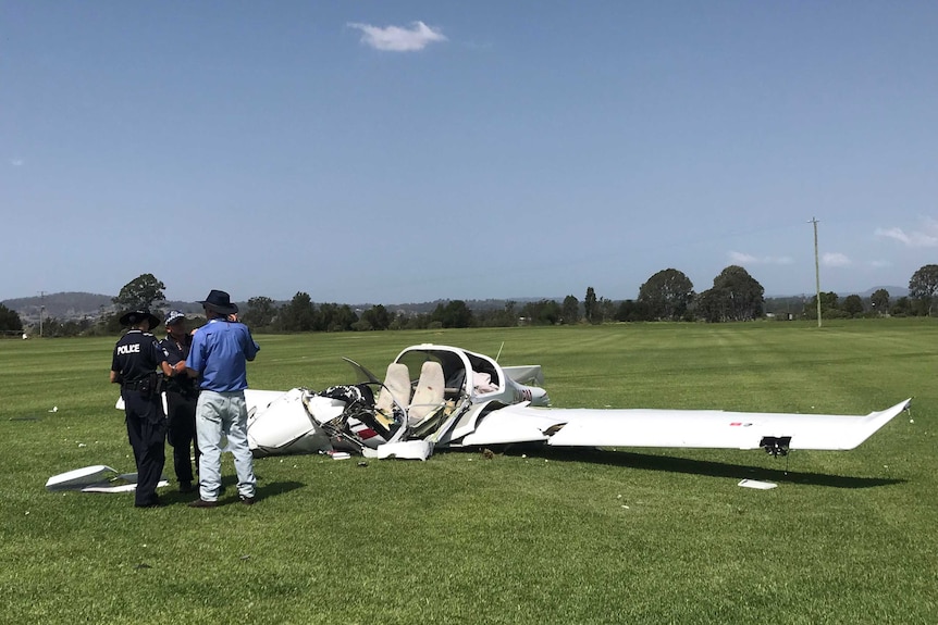A light plane lies crashed in a field with police investigating