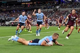 Tom Trbojevic dives over the line as players celebrate behind