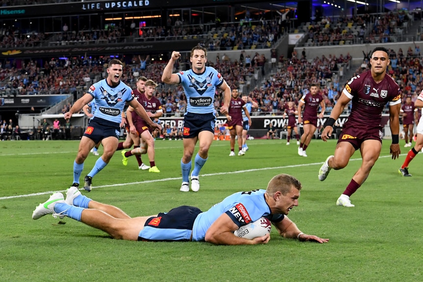 Tom Trbojevic dives over the line as players celebrate behind