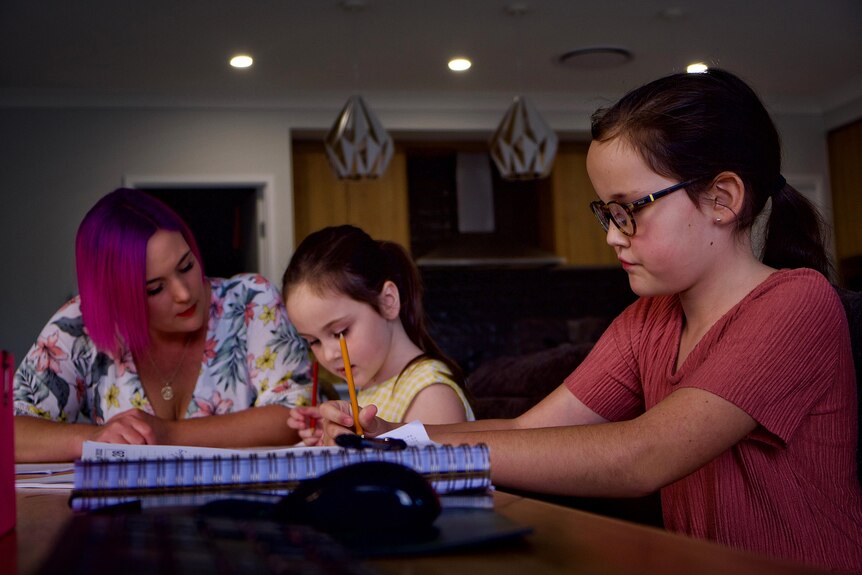 Tara helps her daughters with their school at kitchen table in Logan Reserve home.