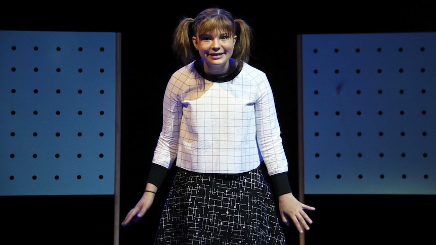 A girl with pigtails on stage during a play's dress rehearsal