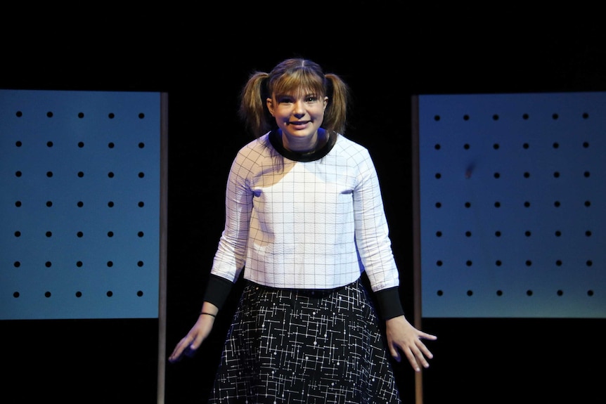 A girl with pigtails on stage during a play's dress rehearsal