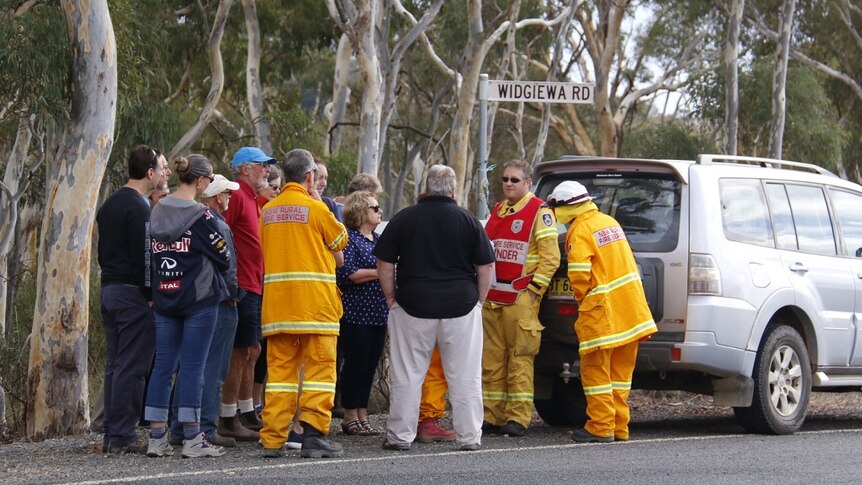 Residents and emergency crews huddle on a street in Carwoola.
