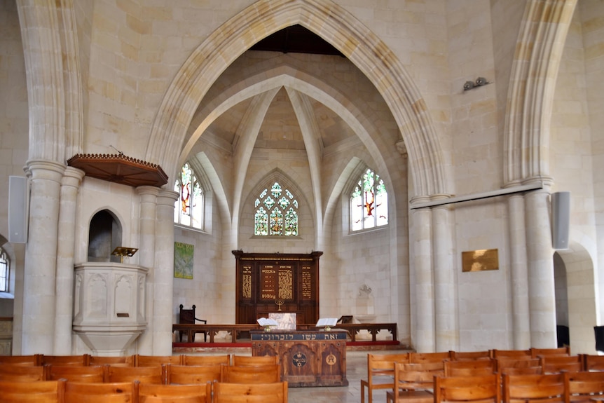 The interior of a sandstone church, with high sculptural windows of stained glass