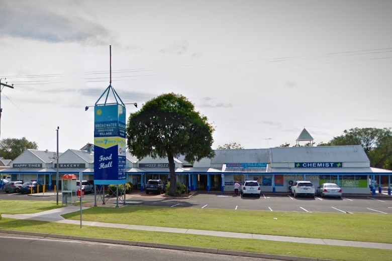 A suburban shopping centre with a grass verge and a number of specialty shops.