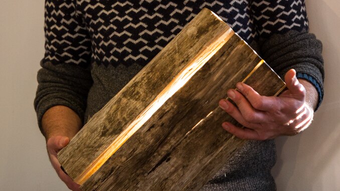 Duncan Meerding holds a cracked log lamp that he created out of Tasmanian wood.