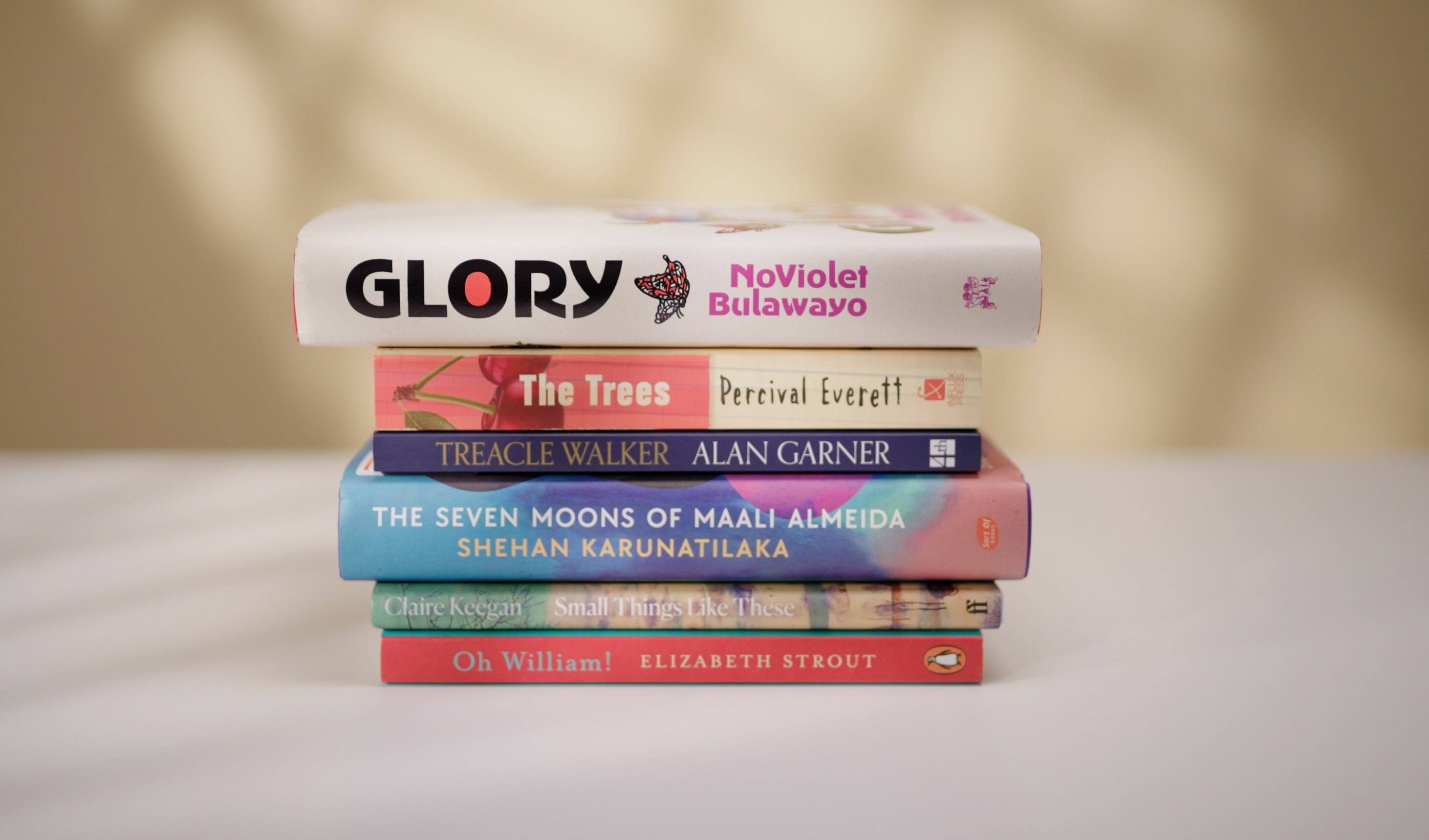 A stack of six books, of various sizes and lengths, as well as different colours, such as red, white and navy