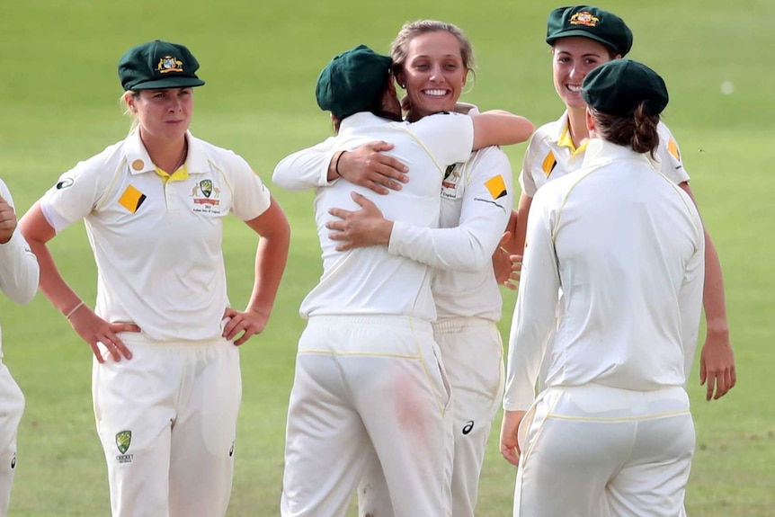 Eight Australian players mull around while a beaming Ashleigh Gardner receives a hug.