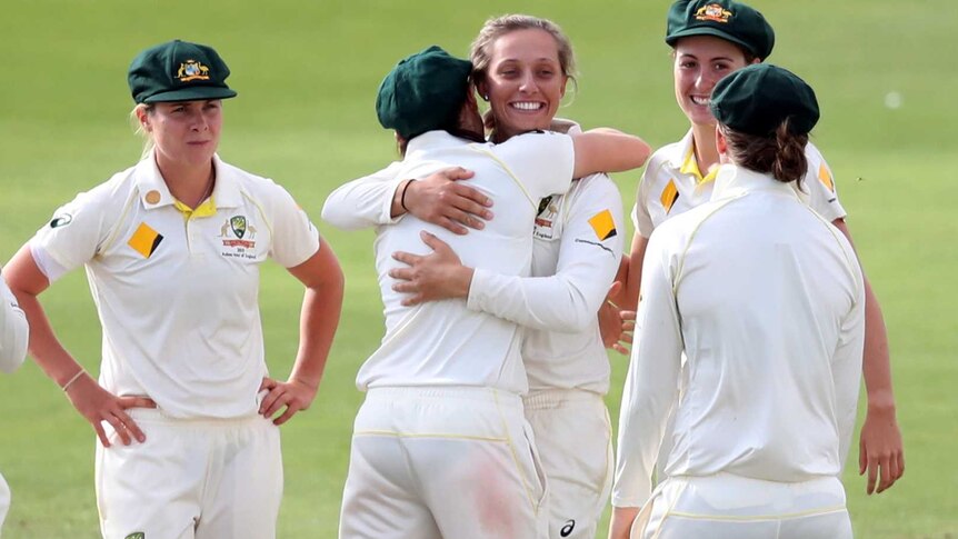 Eight Australian players mull around while a beaming Ashleigh Gardner receives a hug.