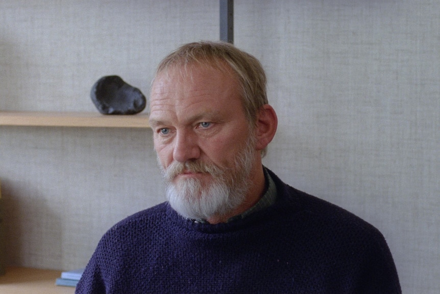 An older man sitting in a bare office in the film A White, White Day