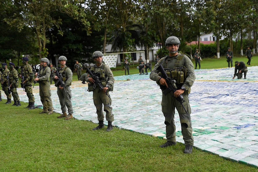 Colombian police and soldiers guard more than 12 tons of seized cocaine