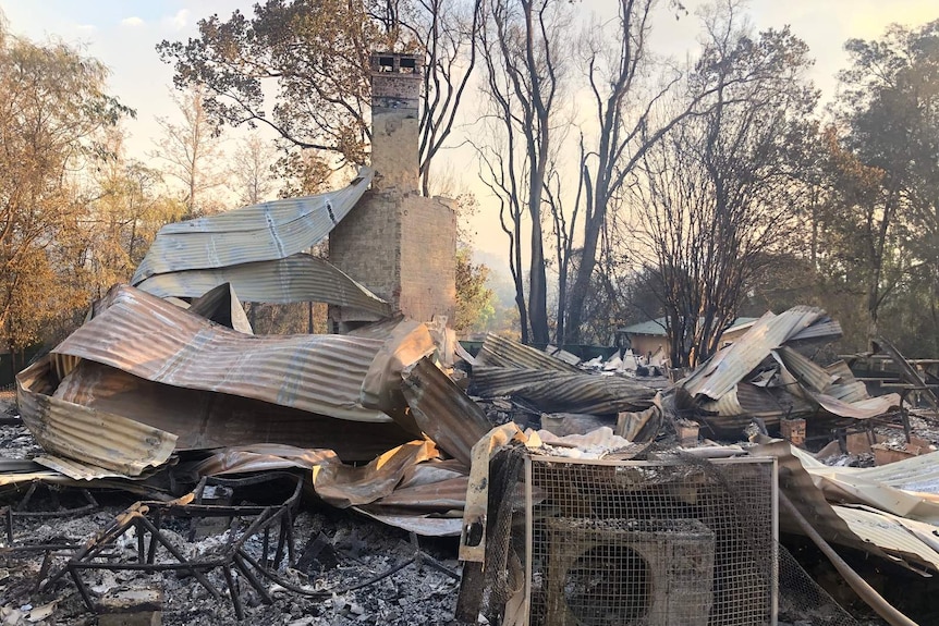 a charred and collapsed brick and tin roof building