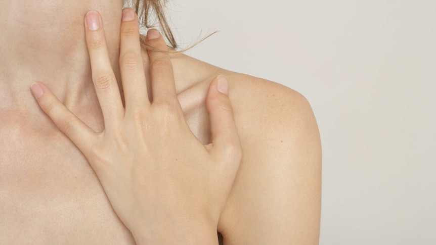 A picture of a woman with her hand on the front left part of her neck and shoulder - over the collarbone