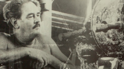 An old photo of a man with a moustache and a wheel