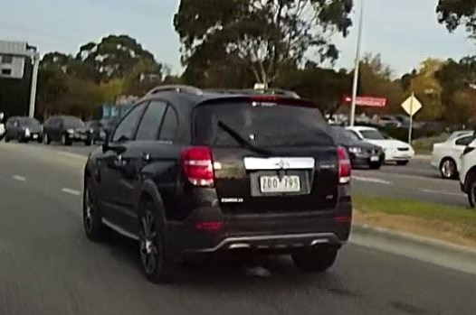 A dashcam photo of a black Holden Captiva driving down a street.