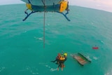 A CQ Rescue helicopter crew winches tourist Levi Verwoest from his overturned catamaran in waters south of Mackay.