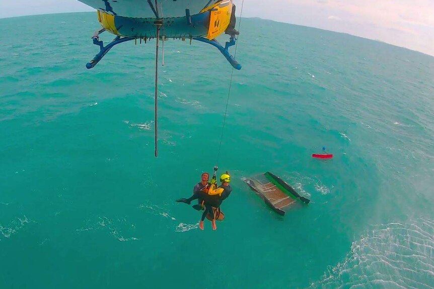 A CQ Rescue helicopter crew winches tourist Levi Verwoest from his overturned catamaran in waters south of Mackay.