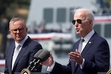 Joe Biden in sunglasses speaking while Anthony Albanese looks on