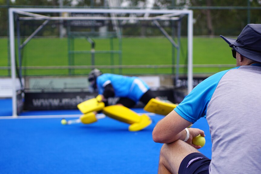 A hockey goalkeeper tries to save a ball in training