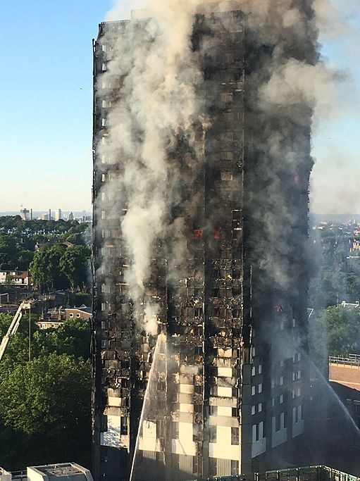 A burnt out tower building surrounded by smoke.