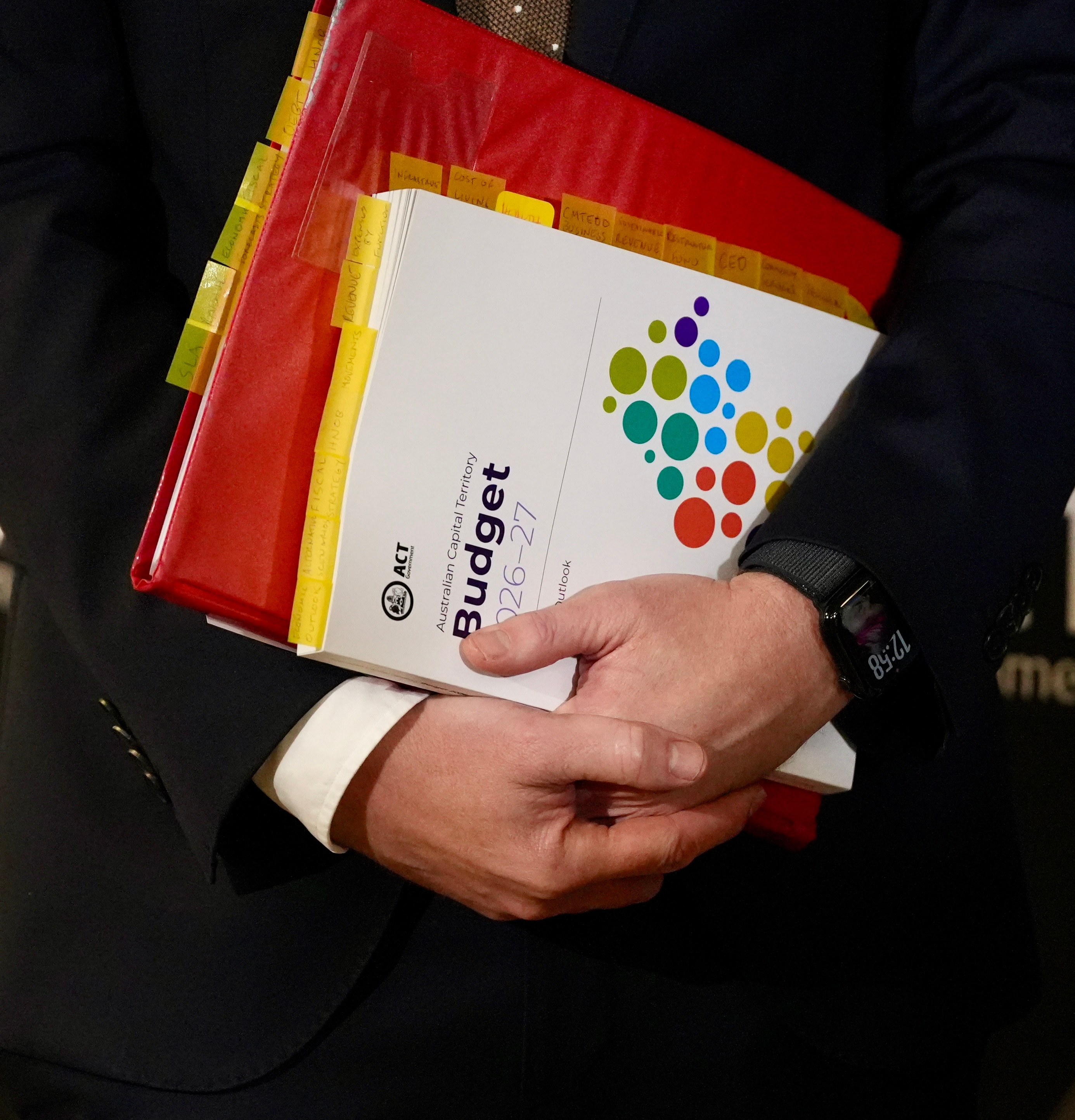 A man's hands hold a stack of budget papers.