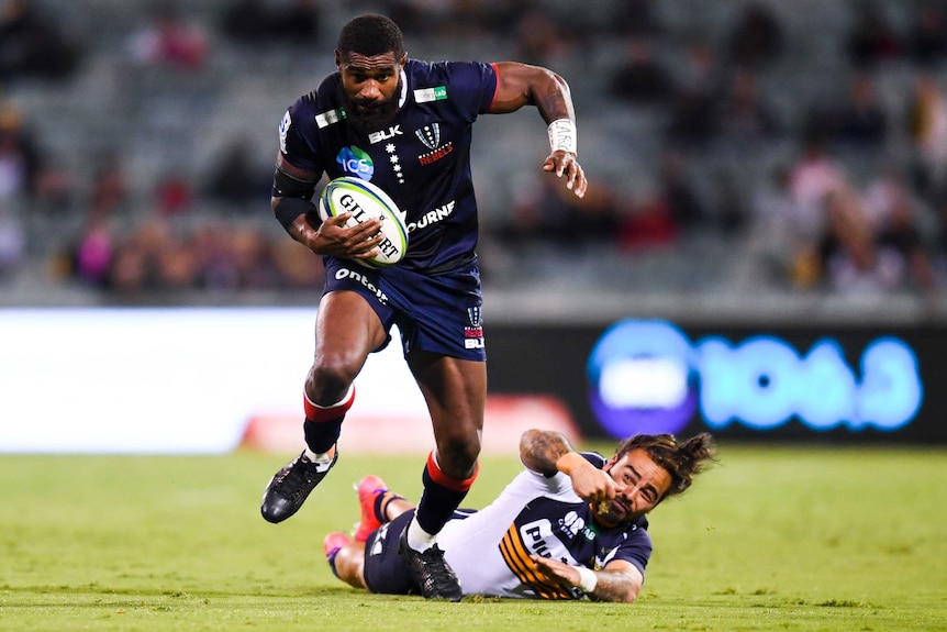 Marika Koroibete holds the ball as he is tackled by Andy Muirhead.