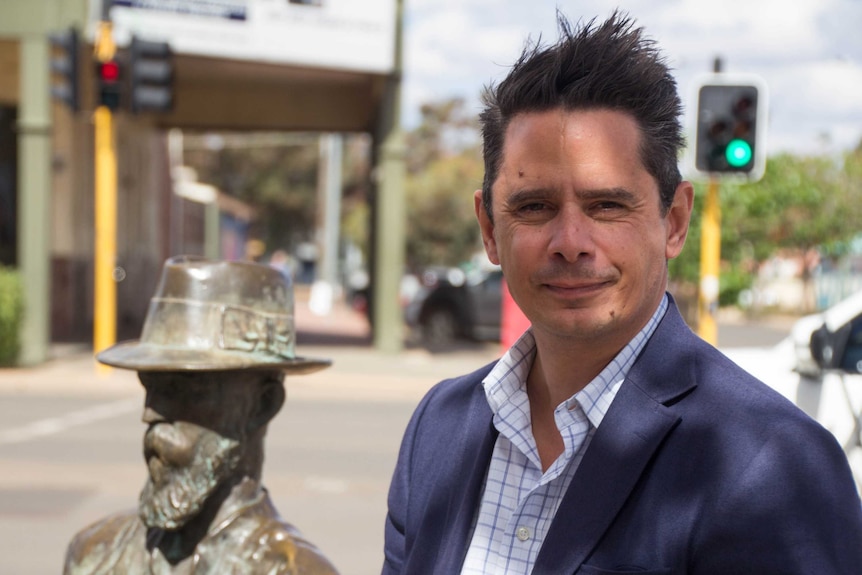 WA Treasurer Ben Wyatt sits next to a statues of Paddy Hannan in Kalgoorlie, Western Australia.