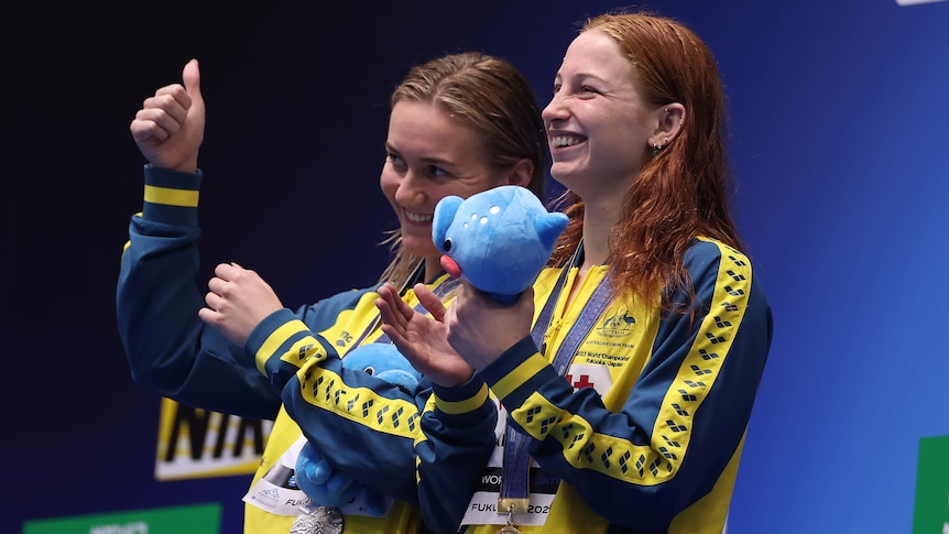 Two Australian female swimmers stand on the medal podium at the World Aquatics Championships.