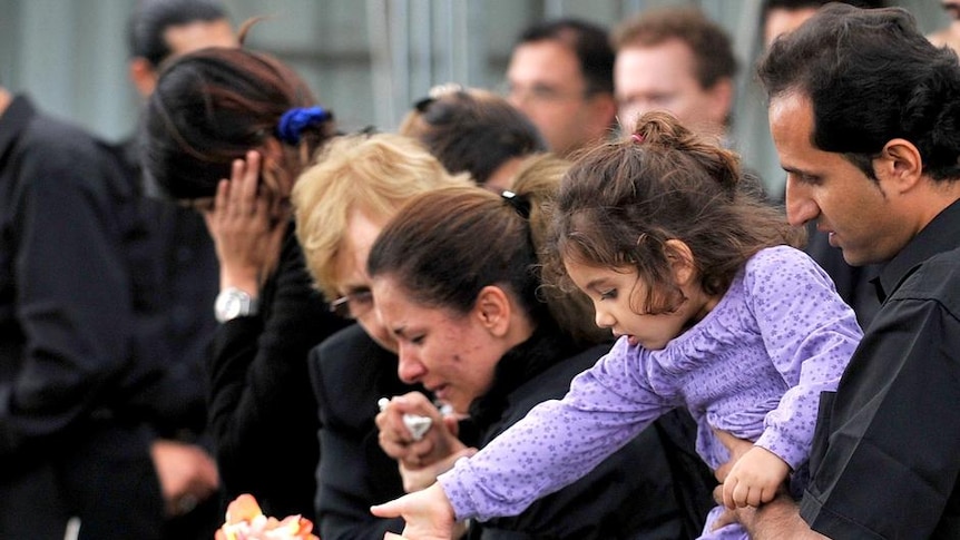 Mourners throw flowers onto coffins at the Castlebrook Cemetery in Sydney