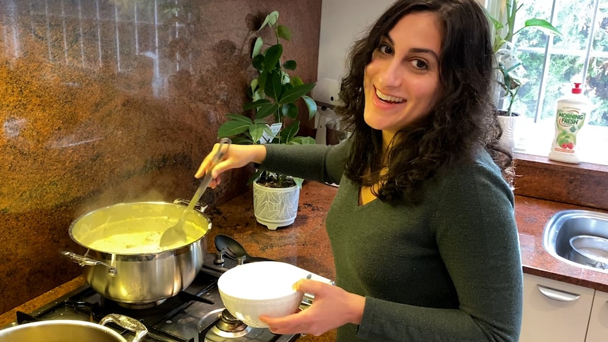 Christina smiles while cooking a pot of dokhwa, a traditional Assyrian stew, in her home kitchen.