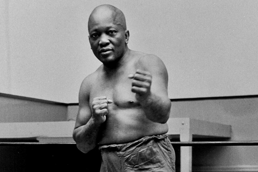 Boxer Jack Johnson poses with his fists out in front of him.