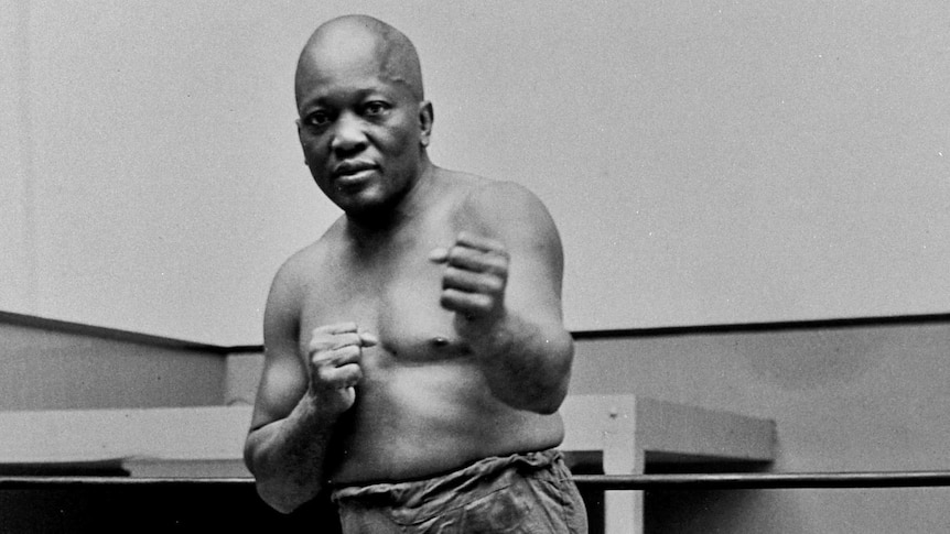 Boxer Jack Johnson poses with his fists out in front of him.