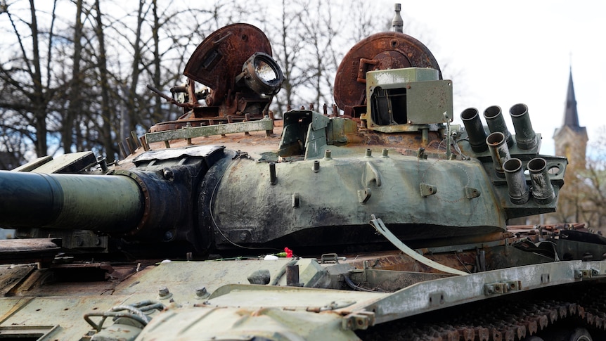 Flower placed on top of burnt Russian tank on display.