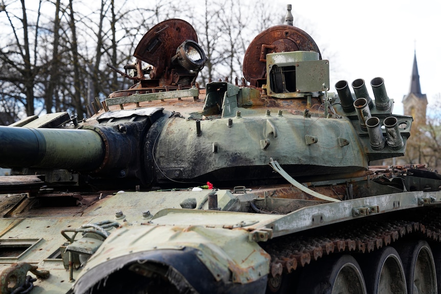 Flower placed on top of burnt Russian tank on display.