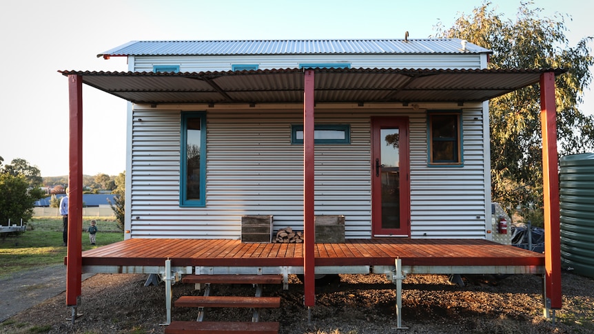 The rear of a small house clad in corrugated iron with a small verandah