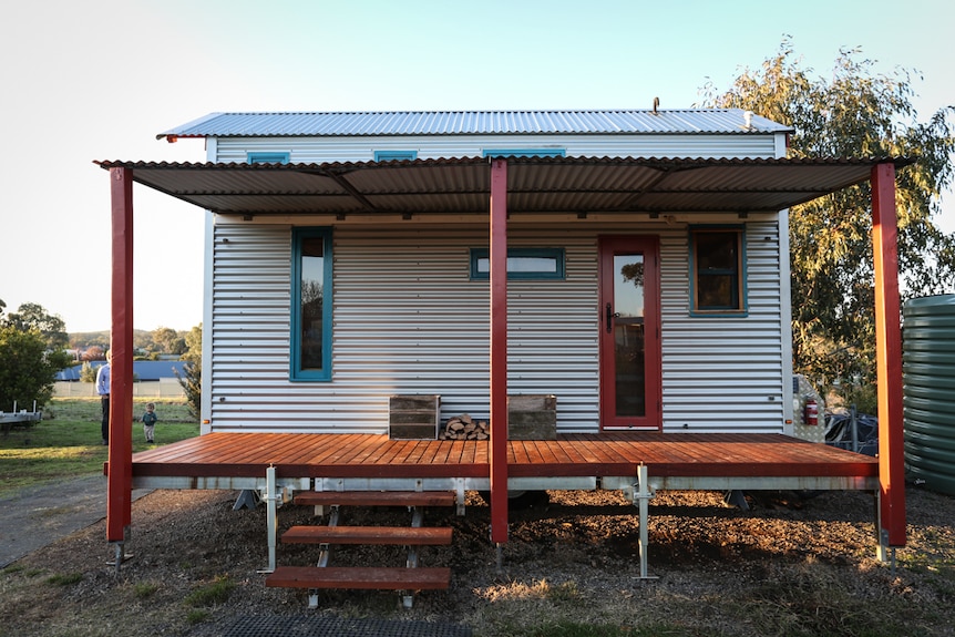 The rear of a small house clad in corrugated iron with a small verandah