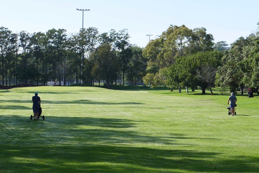 Two golfers walk along the fairway at Marrickville Golf Course, April, 2020.