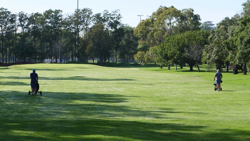 Two golfers walk along the fairway at Marrickville Golf Course, April, 2020.